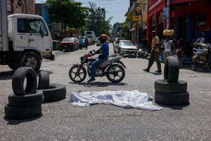(FILES) In this file photo taken on August 26, 2019, dead body covered with a sheet lies on the middle of the road in downtown of Port-au-Prince. - Long confined to the slums, the gangs have gradually extended their control in Haiti and the nearly three million inhabitants of Port-au-Prince are forced to adapt their daily lives to this reality, for fear of being the next victim. "The gangs today reign supreme and lords over the country," laments G�d�on Jean, director of the Center for Analysis and Research in Human Rights, based in the Haitian capital. (Photo by CHANDAN KHANNA / AFP)