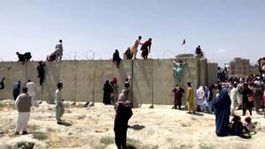 FOTO DE ARCHIVO: Personas trepan un muro de alambre de púas para ingresar al aeropuerto en Kabul, Afganistán, 16 de agosto de 2021, en esta imagen fija tomada de un video. REUTERS TV / vía REUTERS / Foto de archivo