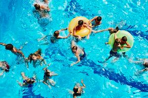 Group of kids playing together in outdoor pool overhead view