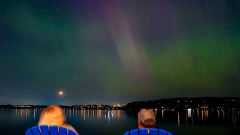 Un grupo de personas admira la aurora boreal que ilumina el lago Washington, en Renton.