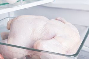 close-up of a whole chicken, against the background of a white refrigerator, in a glass substrate