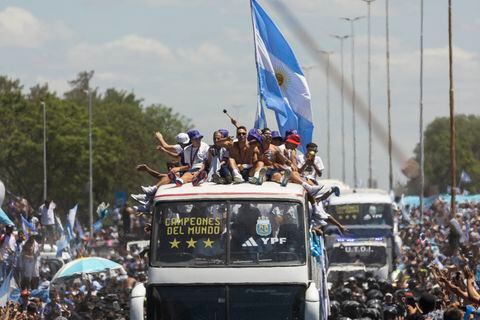 Argentina's players celebrate on board a bus with a sign reading "World Champions" with supporters after winning the Qatar 2022 World Cup tournament as they tour through Buenos Aires' downtown on December 20, 2022. - Millions of ecstatic fans are expected to cheer on their heroes as Argentina's World Cup winners led by captain Lionel Messi began their open-top bus parade of the capital Buenos Aires on Tuesday following their sensational victory over France. (Photo by TOMAS CUESTA / AFP)