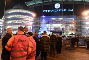 Los delegados revisan los pasaportes covid-19 de los fanáticos mientras hacen fila para ingresar al estadio antes del partido de fútbol de la Premier League entre Manchester City y Leeds en el Etihad Stadium