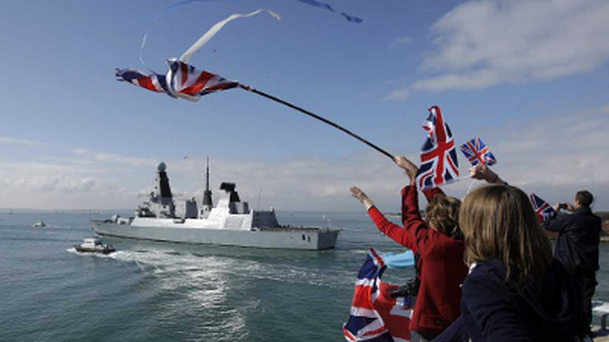 Numerosas personas, algunas con banderas británicas, se dieron cita en el puerto de Portmouth para decir adiós a la tripulación del "HMS Dauntless".