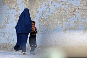 Una mujer vestida con burka camina con una niña por una calle en Kabul el 7 de mayo de 2022. - El 7 de mayo, los talibanes impusieron algunas de las restricciones más duras a las mujeres de Afganistán desde que tomaron el poder, ordenándoles cubrirse completamente en público, idealmente con el burka tradicional. (Foto de Ahmad SAHEL ARMAN / AFP) /  La mención errónea que aparece en los metadatos de esta foto de Ahmad SAHEL ARMAN ha sido modificada en los sistemas de AFP de la siguiente manera: [Corrección de calidad]. Elimine inmediatamente las menciones erróneas de todos sus servicios en línea y elimínelos de sus servidores. Si ha sido autorizado por AFP para distribuirlo(s) a terceros, asegúrese de que las mismas acciones sean realizadas por ellos. El incumplimiento puntual de estas instrucciones implicará responsabilidad de su parte por cualquier uso continuado o posterior a la notificación. Por lo tanto, le agradecemos mucho toda su atención y pronta acción. Lamentamos las molestias que esta notificación pueda causar y quedamos a su disposición para cualquier información adicional que necesite.