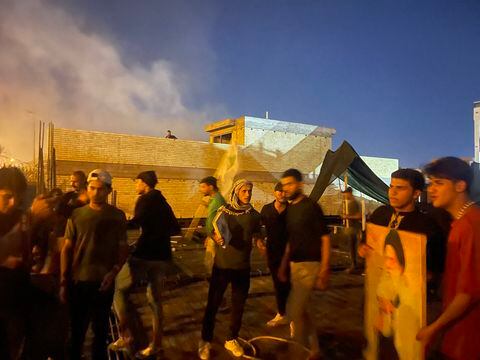 Los manifestantes se paran en lo alto de un edificio junto a la embajada de Suecia en Bagdad el 20 de julio de 2023. Irak condenó el incendio de la embajada de Suecia en Bagdad por parte de los manifestantes, dijo su Ministerio de Relaciones Exteriores, y pidió a las fuerzas de seguridad que identifiquen a los responsables.