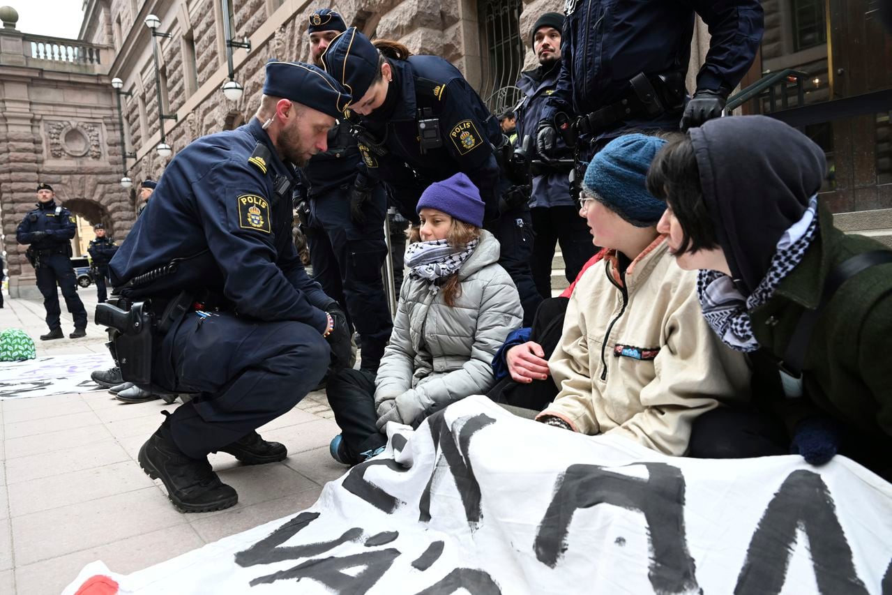La policía habla con la activista climática Greta Thunberg, en el centro, mientras se manifiesta con un grupo de activistas frente al edificio del Parlamento sueco, en Estocolmo