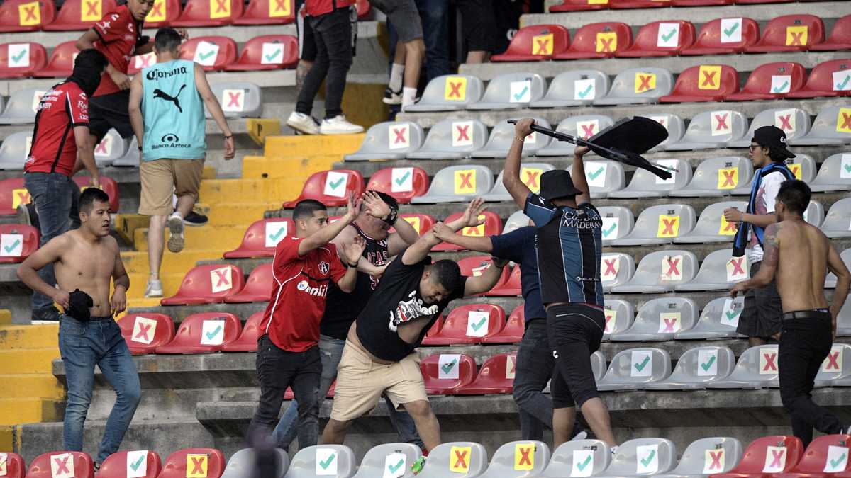 Supporters of Atlas fight with supporters of Queretaro during the Mexican Clausura tournament football match between Queretaro and Atlas at Corregidora stadium in Queretaro, Mexico on March 5, 2022. - A match between Mexican football clubs was called off March 5, 2022 after violence by opposing fans spilled onto the field. The game between Queretaro and Atlas at La Corregidora stadium in the city of Queretaro  -- the ninth round of the 2022 Clausura football tournament -- was in its 63rd minute when fights between opposing fans broke out. (Photo by AFP)