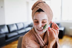 Woman using jade roller on her face at home. Young girl massaging face by jade roller. Self-care facial massage, anti-aging lifting skincare procedure
