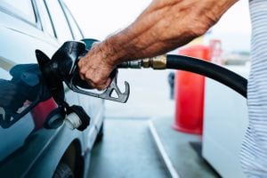 Cerrar las manos de un hombre mayor repostando su vehículo en una gasolinera - Concepto de aumento del precio del petróleo