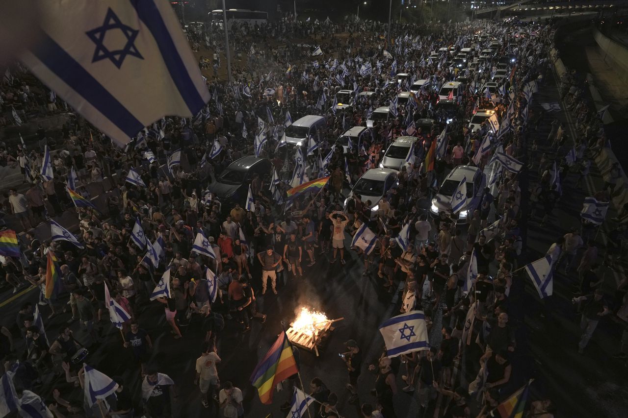 Los manifestantes encendieron un fuego mientras bloqueaban el tráfico en una carretera que cruza la ciudad durante una protesta contra los planes del gobierno de Netanyahu para reformar el sistema judicial, en Tel Aviv, el lunes 24 de julio de 2023.