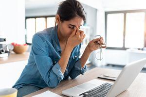 Foto de mujer de negocios estresada que trabaja desde casa en una computadora portátil con aspecto preocupado, cansado y abrumado.