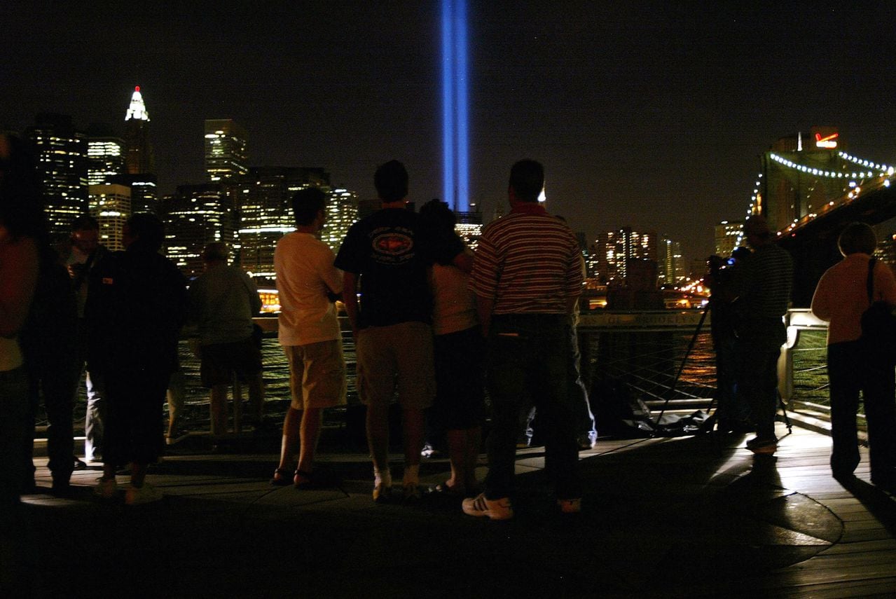 La gente mira las luces tributo de las torres gemelas que iluminan el cielo en memoria de los ataques terroristas del 11 de septiembre de 2004 en Brooklyn, Nueva York.
