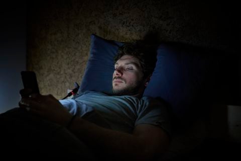 Hombre en la cama manipula su celular