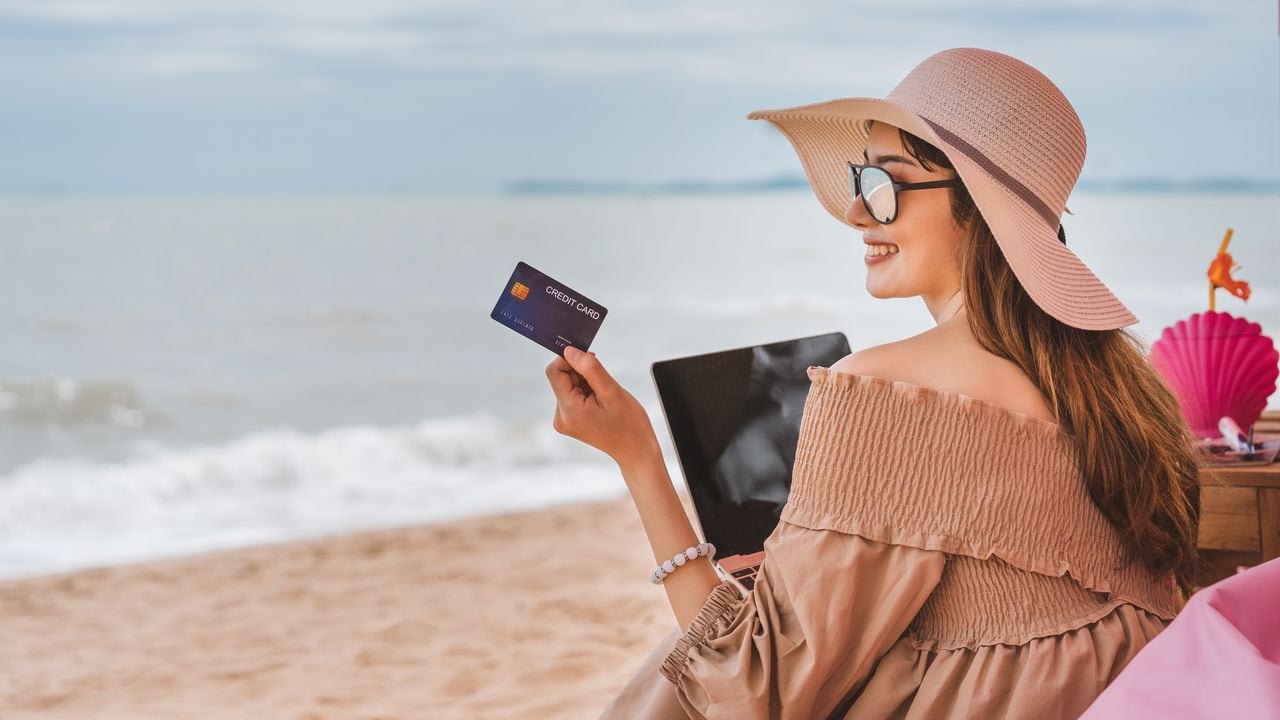 On vacation at Pattaya beach, asian traveler woman with floppy hat use credit card in luxury cafe.