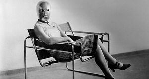 Estudiante de la Bauhuaus sentada en la silla Wassily, de Marcel Breuer, con máscara de Oskar Schlemmer.
