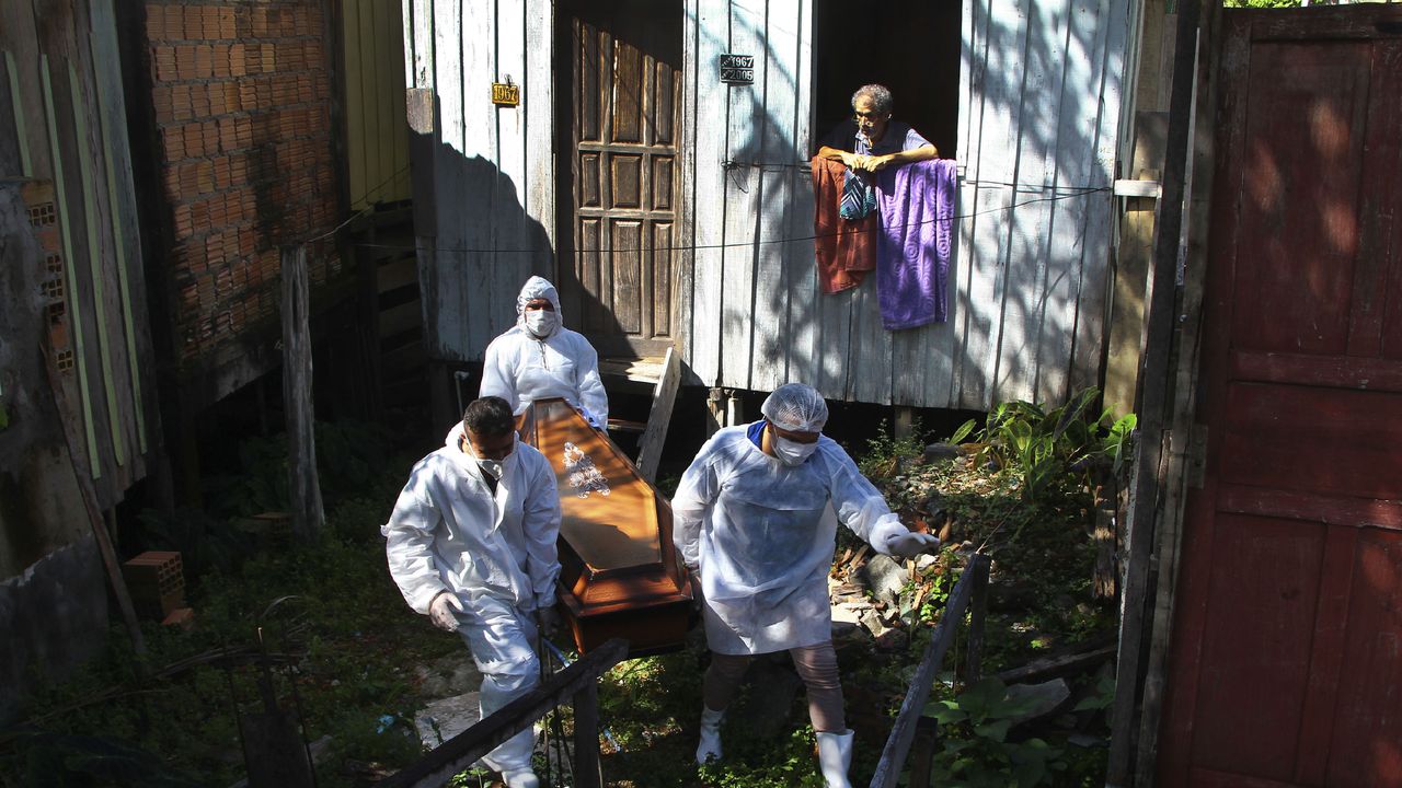 Un familiar observa cómo los trabajadores del servicio funerario público retiran el cuerpo de Amelia Dias Nascimento, de 94 años, quien murió por complicaciones relacionadas con el COVID-19 en su casa, en Manaus, estado de Amazonas.  (Foto AP / Edmar Barros, archivo)